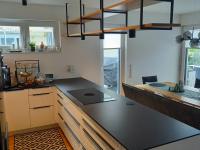 Küche in weiß mit schwarzer Arbeitsplatte und hängendem Regal